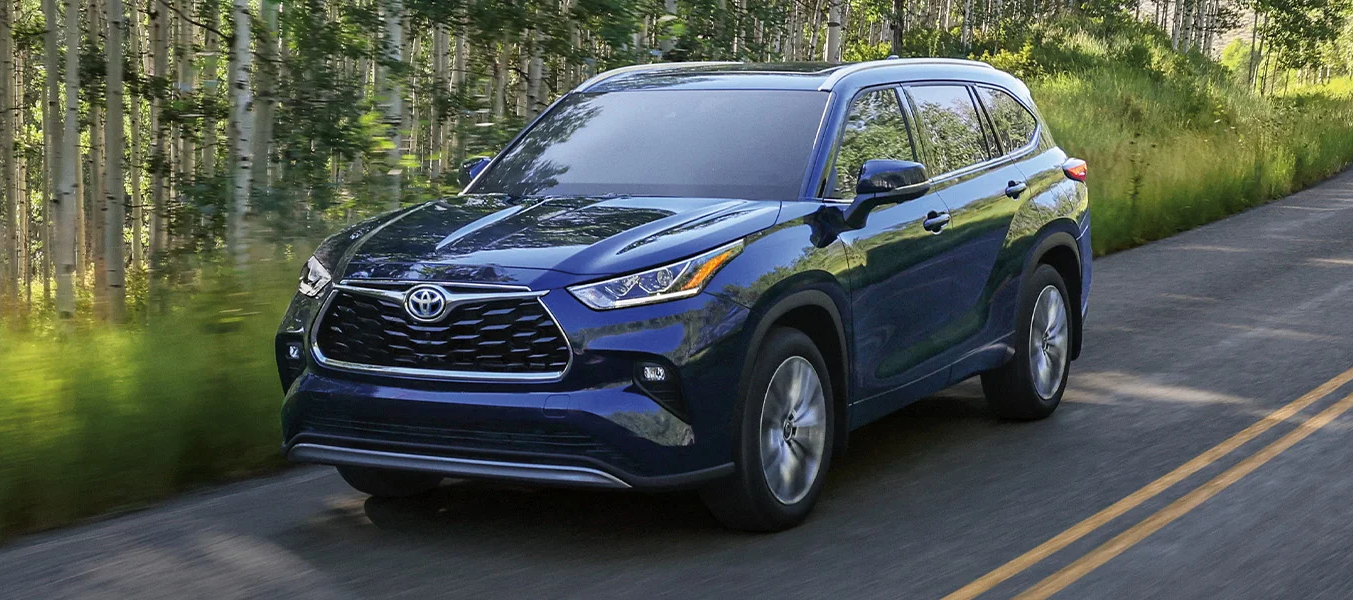 The 2023 Toyota Highlander Hybrid driving through the forest
