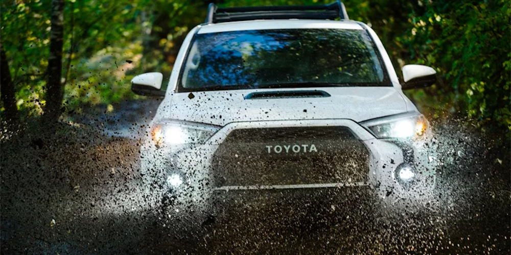 A 2024 Toyota 4Runner driving through some mud dramatically